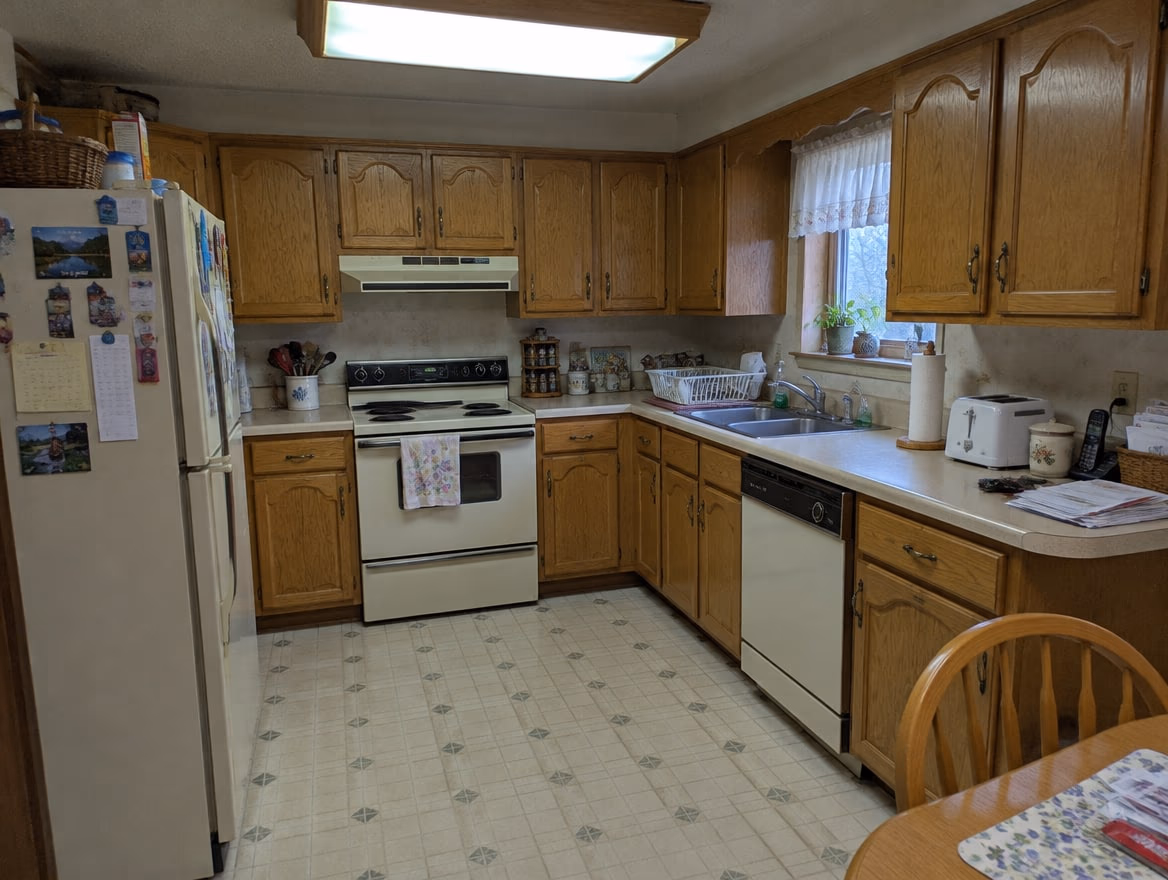 A dated 1990s kitchen with honey oak arched cabinets, beige laminate counters and almond appliances